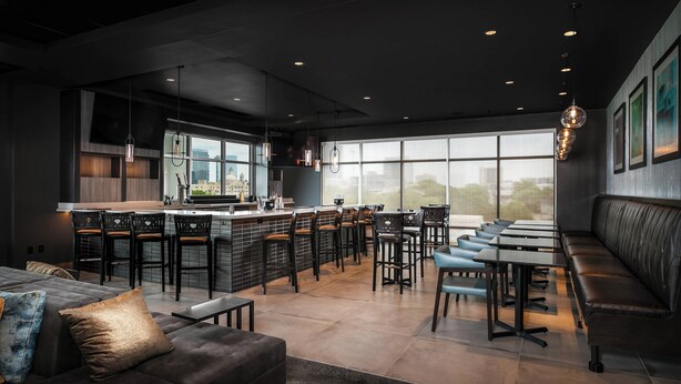A modern restaurant with a bar area, seating, and large windows.