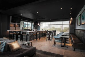 A modern restaurant with a bar area, seating, and large windows. - TownePlace Suites by Marriott Nashville Midtown (Nashville)