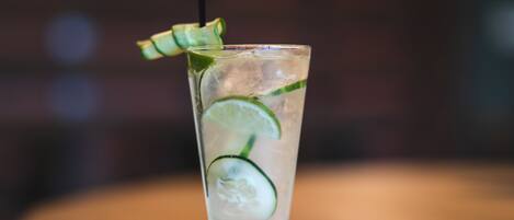 A tall glass with ice cubes, lime slices, and a straw, placed on a wooden surface.