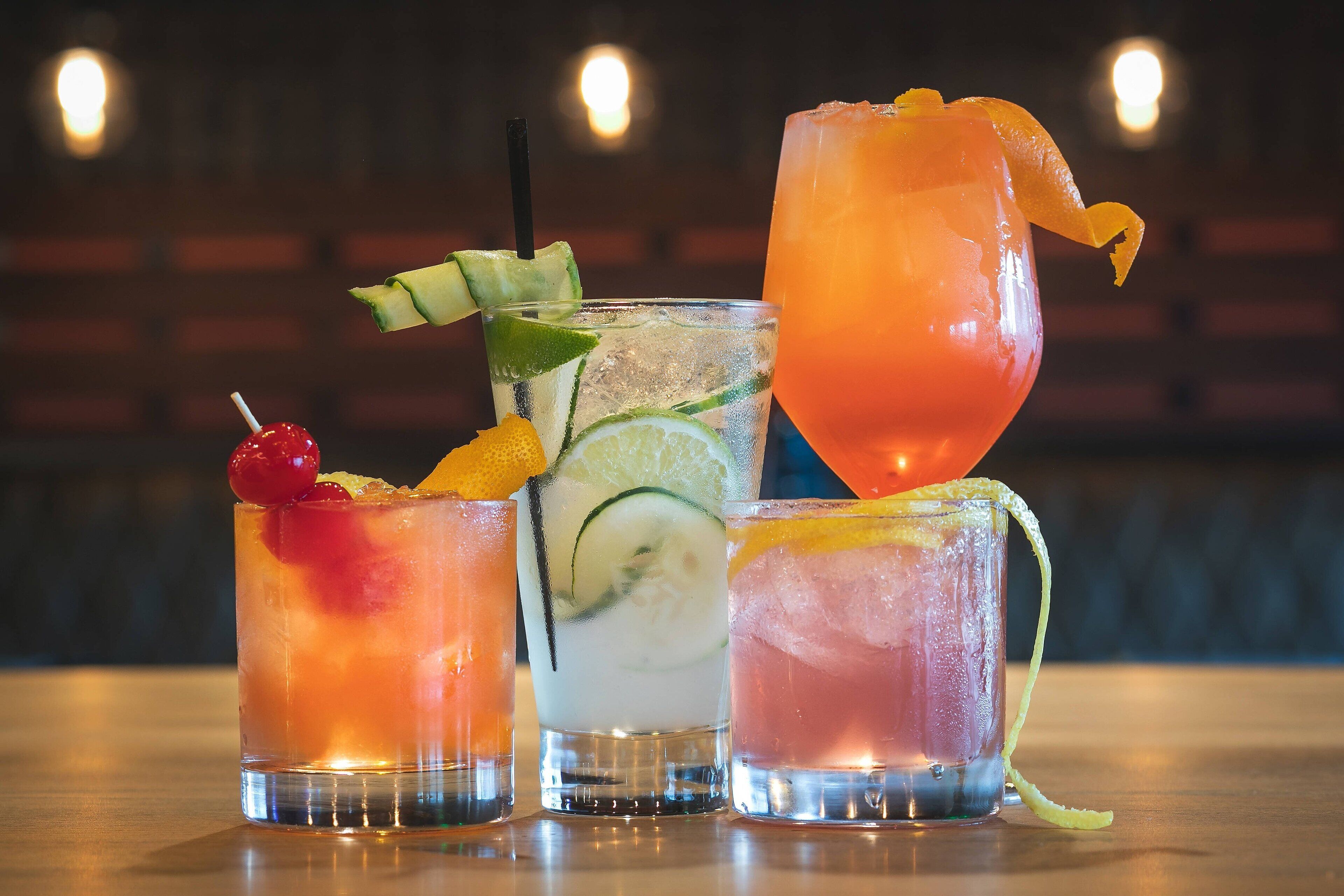 Three cocktails with garnishes and a lime slice in a glass.