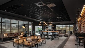 A modern lounge area with a sofa, armchairs, and a bar area with stools.