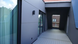 A modern building with a narrow corridor, large glass windows, and a tiled floor. - Meyn's Apartments & Hotel (Soltau)