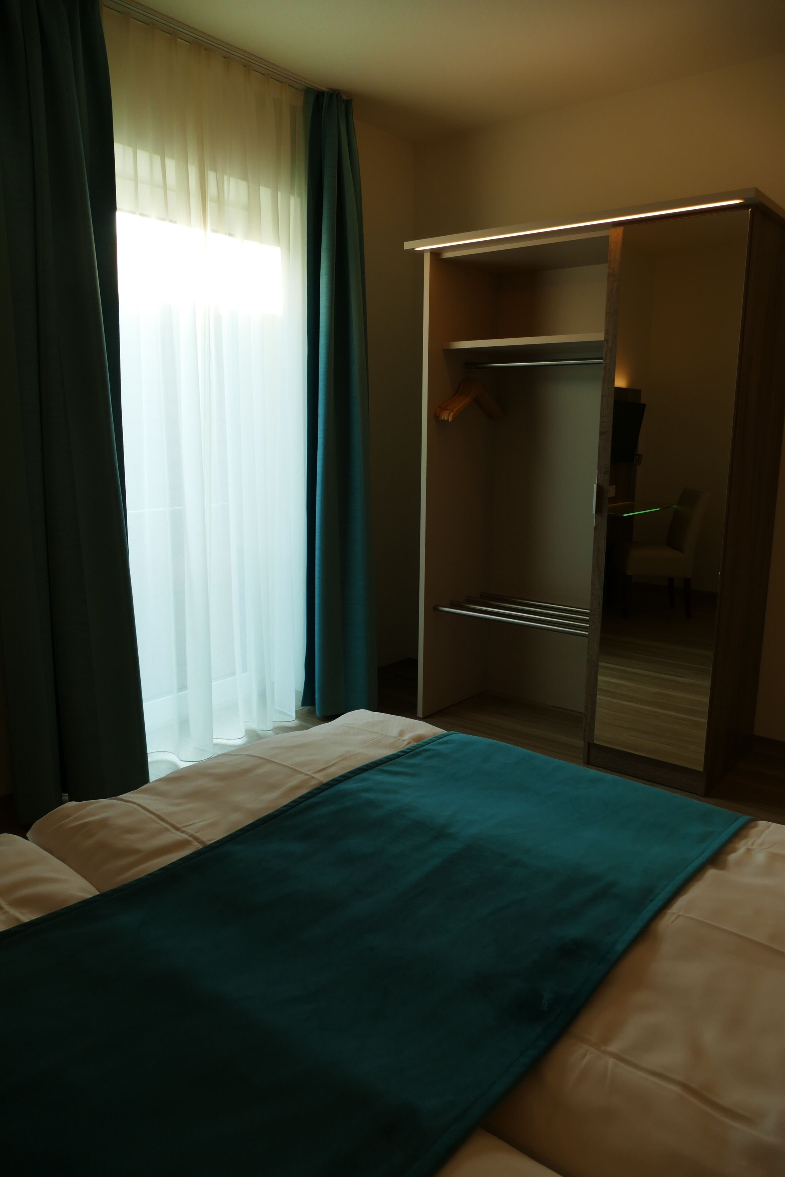 A hotel room with a bed, a wardrobe, and a mirror.