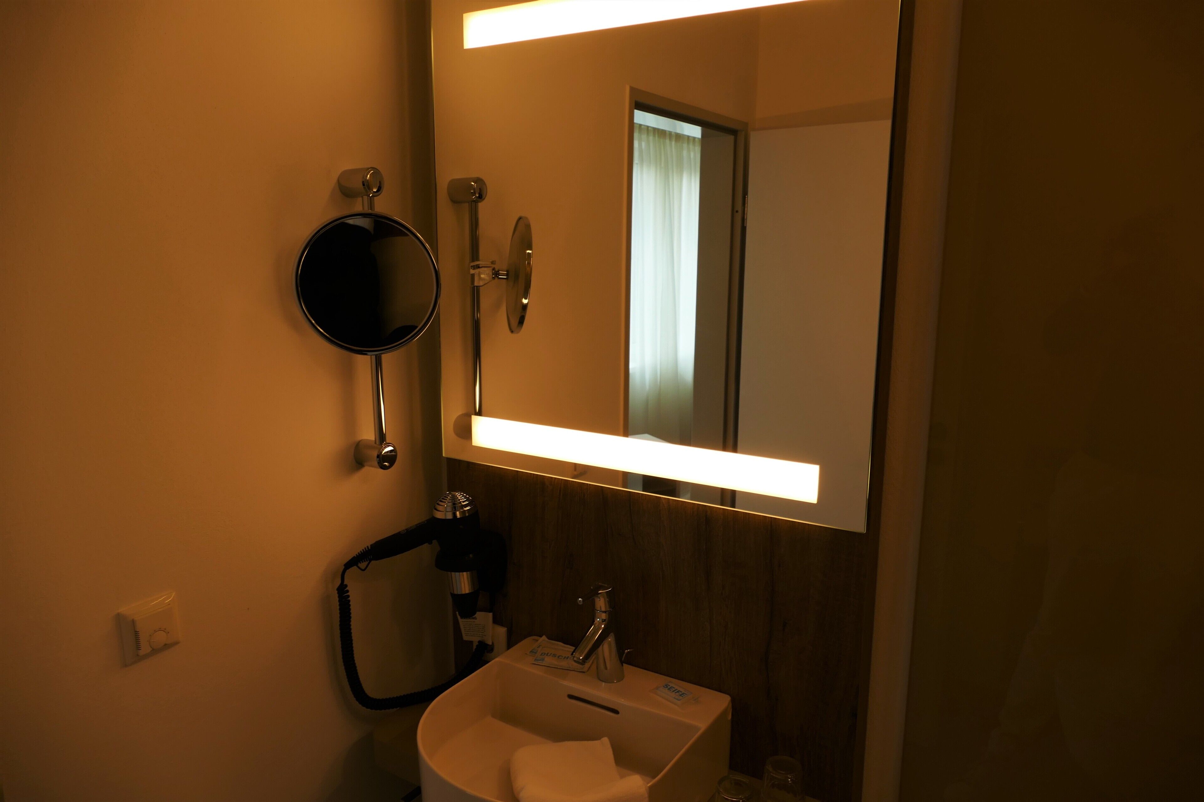 Ein Badezimmer mit Spiegel, Waschbecken und Handtuchhalter.