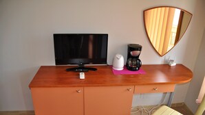 Un petit bureau orange, équipé d’une télévision, d’une machine à café et d’un miroir.