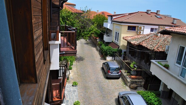 Une ruelle étroite pavée, bordée d’immeubles d’habitation dotés de balcons et de toits en tuiles.