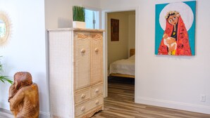 A bedroom with a bed, a wicker wardrobe, a Buddha statue, and a painting on the wall. - Tropical Hideway (Oakland Park)