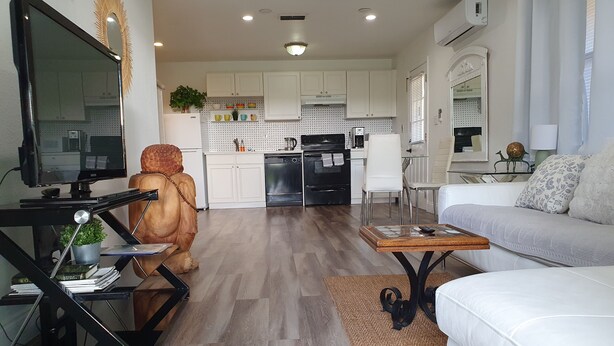A modern living room with a white sofa, a coffee table, and a TV on a stand. - Tropical Hideway (Oakland Park)