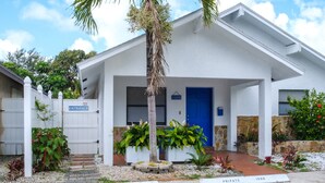 A private entrance with a blue door, a palm tree, and a stone wall with plants. - Tropical Hideway (Oakland Park)