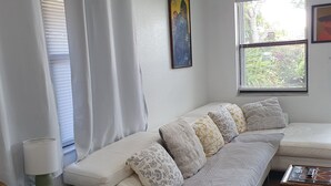 A modern living room with a white sofa, a glass coffee table, and a wooden floor. - Tropical Hideway (Oakland Park)