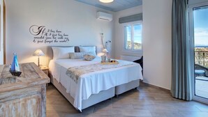 Ett sovrum med en säng, sänglampor, ett dekorativt citat på väggen, en luftkonditioneringsanläggning och utsikt genom ett fönster.