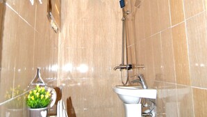 Un bagno con un lavandino bianco, un soffione doccia a mano e un porta asciugamani.