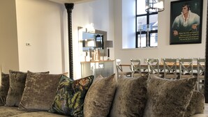 A living room with a sectional sofa, a dining area with a table and chairs, and a large window with natural light. - East Church House (Strathaven)