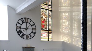 A conference room with a large clock, a stained glass window, and a table with chairs. - East Church House (Strathaven)