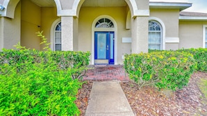 A house with a blue door, a covered porch, and a brick pathway leading to the entrance. - Famosa Villa (Kissimmee)