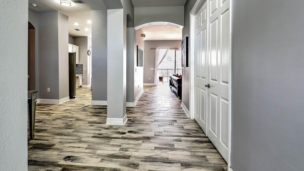 A hallway with a herringbone patterned floor, white walls, and a door on the right. - Famosa Villa (Kissimmee)