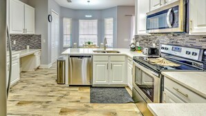 A modern kitchen with white cabinets, a stainless steel dishwasher, a built-in oven, and a microwave. - Famosa Villa (Kissimmee)