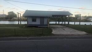 Un pequeño edificio de una sola planta con techo de metal, ubicado cerca de una masa de agua.