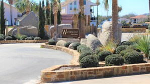 A hotel entrance with a sign for 'Waterfront Bar & Grill' and a pool area with palm trees and rocks.
