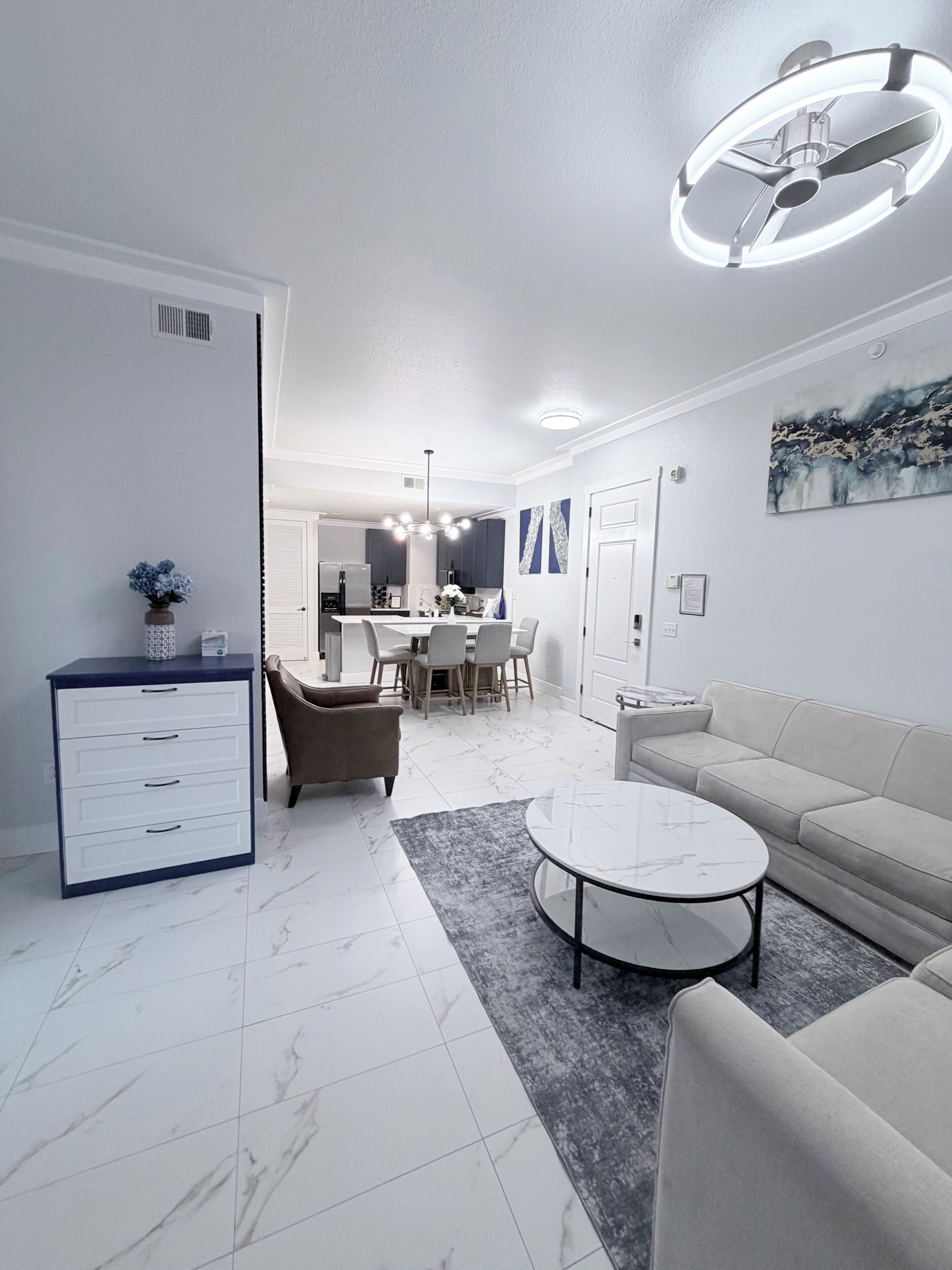 A modern living room with a sofa, coffee table, and a dining area with chairs and a table.