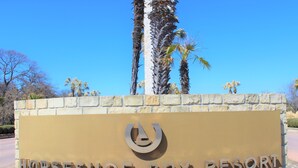 A sign for Horseshoe Bay Resort with a clear sky and palm trees in the background.