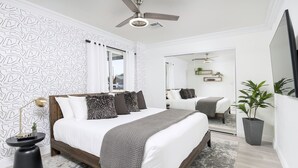 A modern bedroom with a wooden bed, a ceiling fan, a large mirror, and a potted plant. - 5 Min to Old Town • Heated Pool • Hot Tub • Fire Pit (Scottsdale)