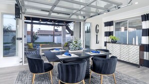 A modern dining area with a glass-enclosed patio, a black table set for four, and a view of the outdoors. - 5 Min to Old Town • Heated Pool • Hot Tub • Fire Pit (Scottsdale)