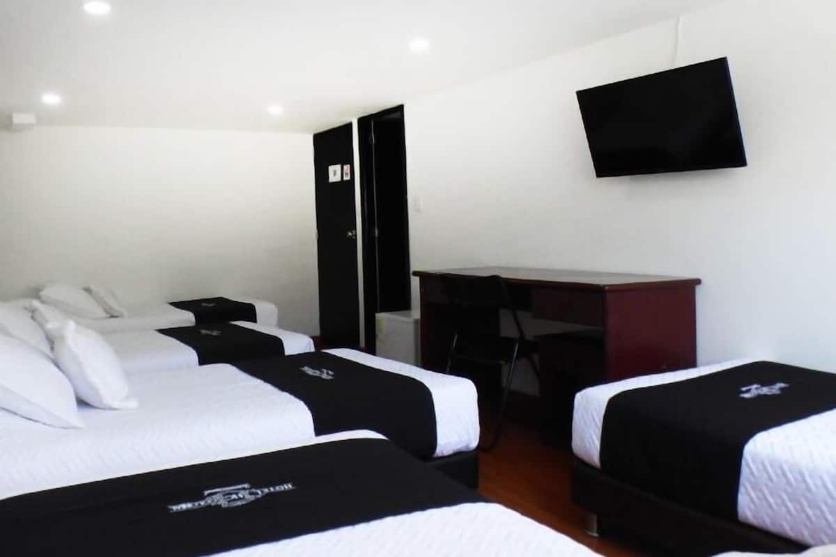 Ein Hotelzimmer mit zwei Betten, einem Schreibtisch, einem Stuhl und einem an der Wand befestigten Flachbildfernseher.