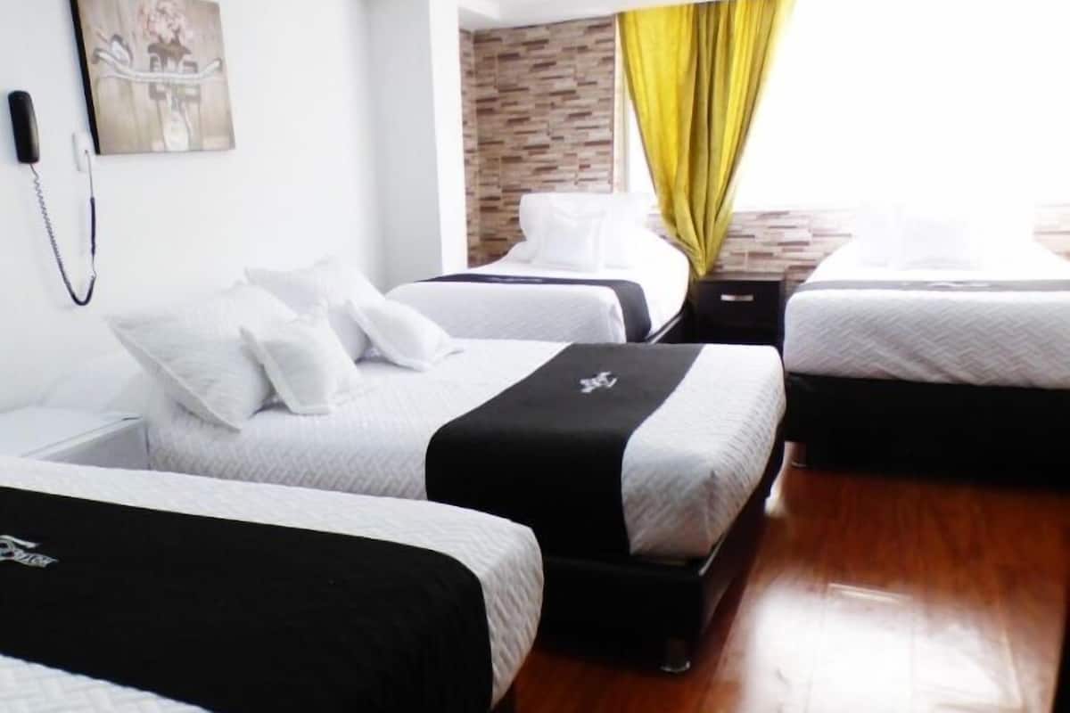 Ein Hotelzimmer mit zwei Betten, Holzboden, einer Wand mit Backsteinakzent und einem Gemälde an der Wand.