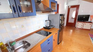 Una cocina compacta con un lavamanos de acero inoxidable, armarios de madera y un horno empotrado.