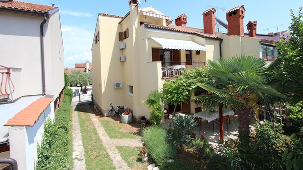Un edificio residencial con un patio ajardinado, un camino y una bicicleta.