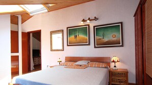 Un dormitorio con una cama de madera, una mesita de noche con lámpara y tres cuadros enmarcados en la pared.