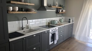 Una cocina moderna con armarios grises, encimera blanca, horno empotrado y pileta de acero inoxidable.
