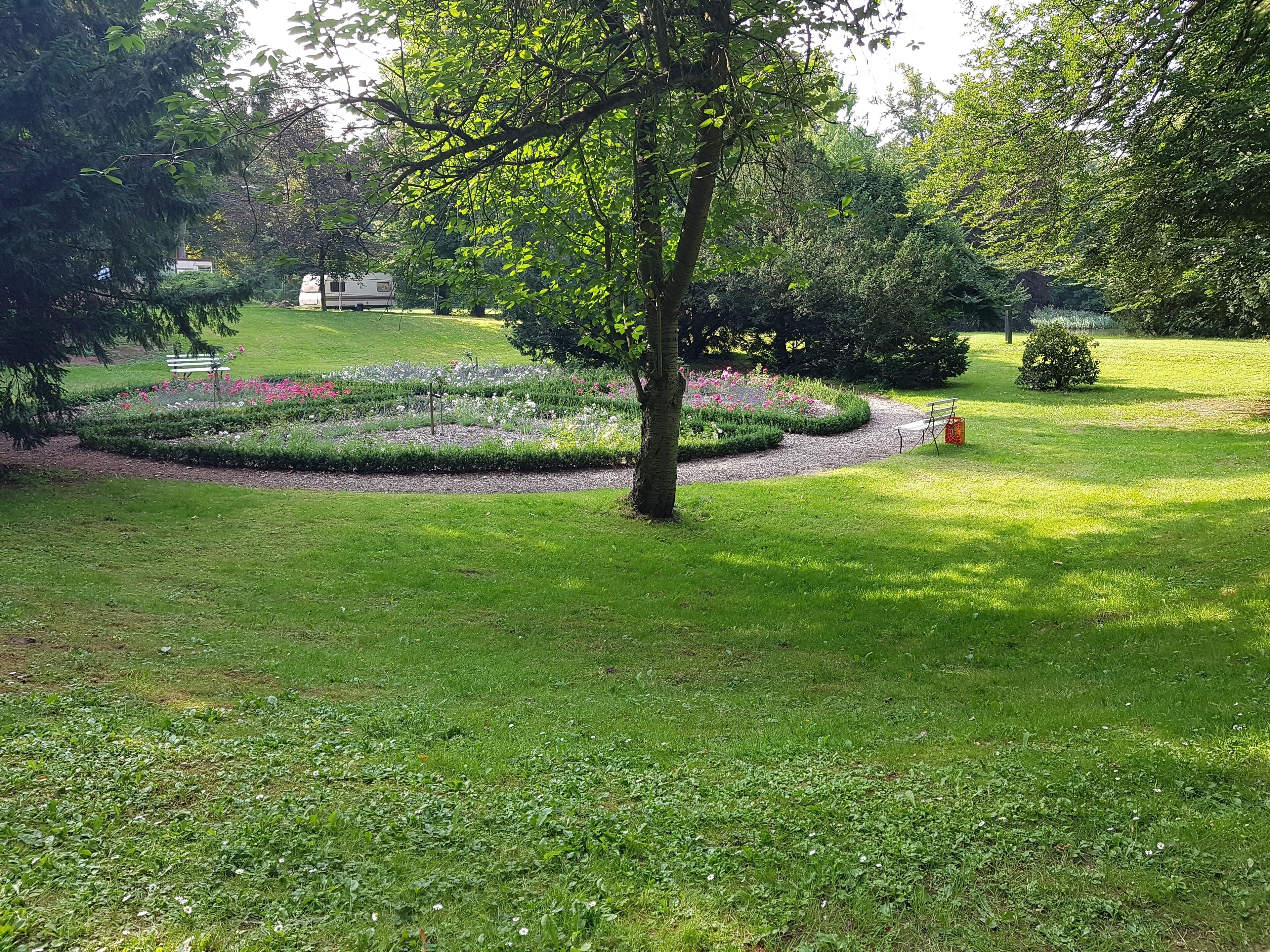 A well-maintained garden with a central flower bed, a bench, and a small tree.