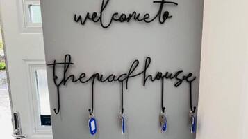 Un letrero en la pared con el texto 'welcome to the past house' y un juego de llaves colgando debajo.
