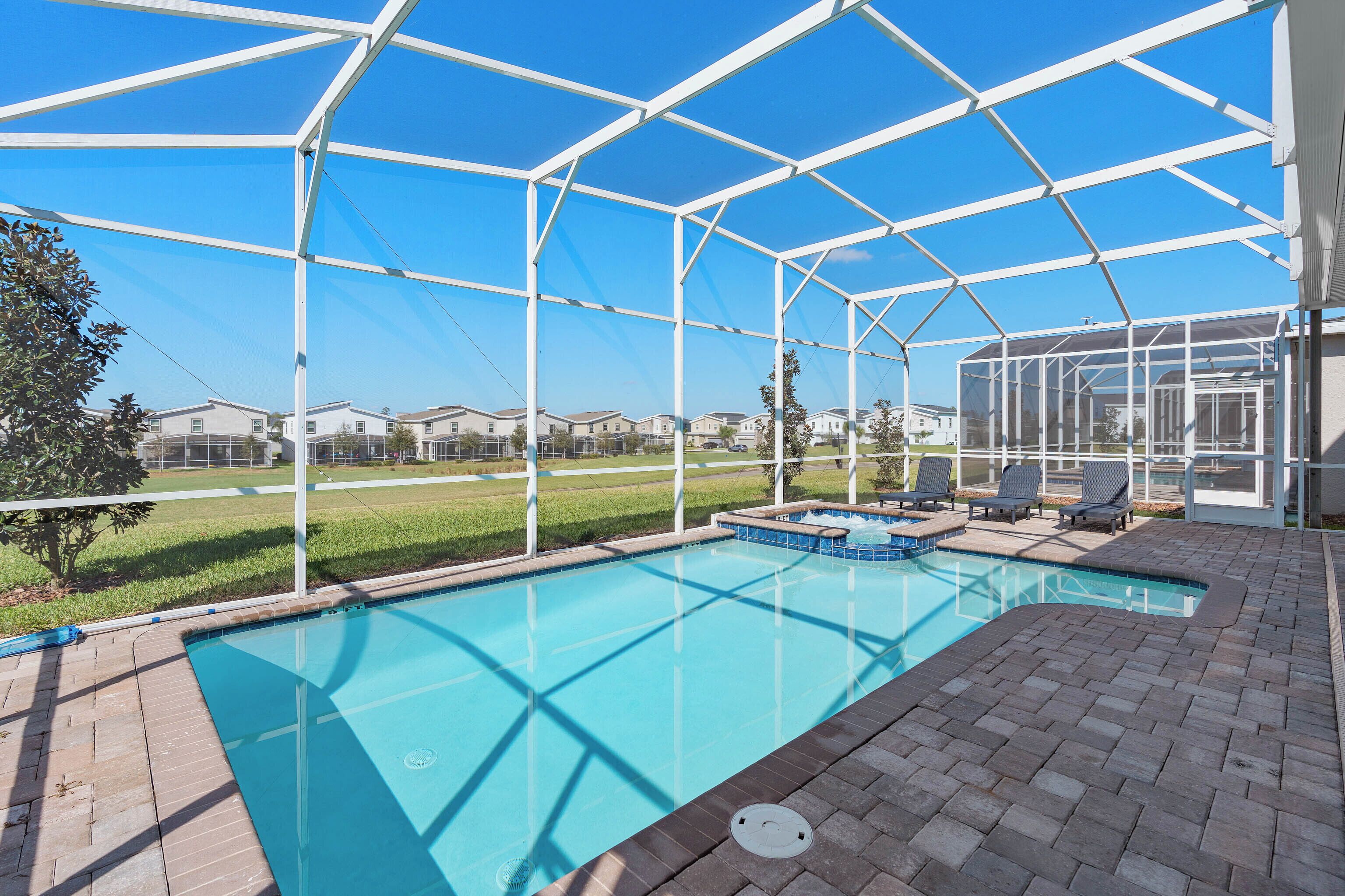 A swimming pool with a covered area, surrounded by a brick deck and lounge chairs.