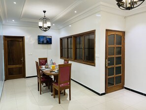 Un comedor con una mesa de madera, sillas y un televisor montado en la pared.