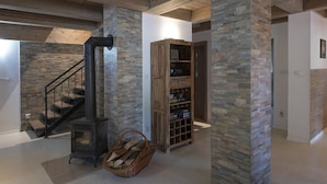 Un intérieur spacieux agrémenté d’un mur en pierres apparentes, d’un escalier en bois et d’une bibliothèque intégrée en bois avec des étagères.