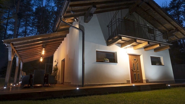 Une maison moderne dotée d’un porche abrité, d’un balcon et d’une petite fenêtre.
