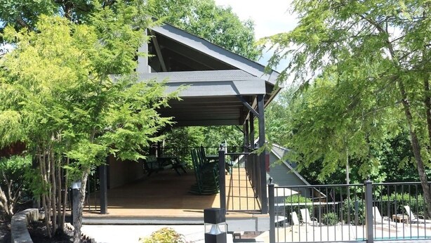 A covered outdoor area with a staircase leading to a building, surrounded by trees and a fence. -  2 minutes to Parkway, 5 minutes to The Island & Dollywood!  (Pigeon Forge)
