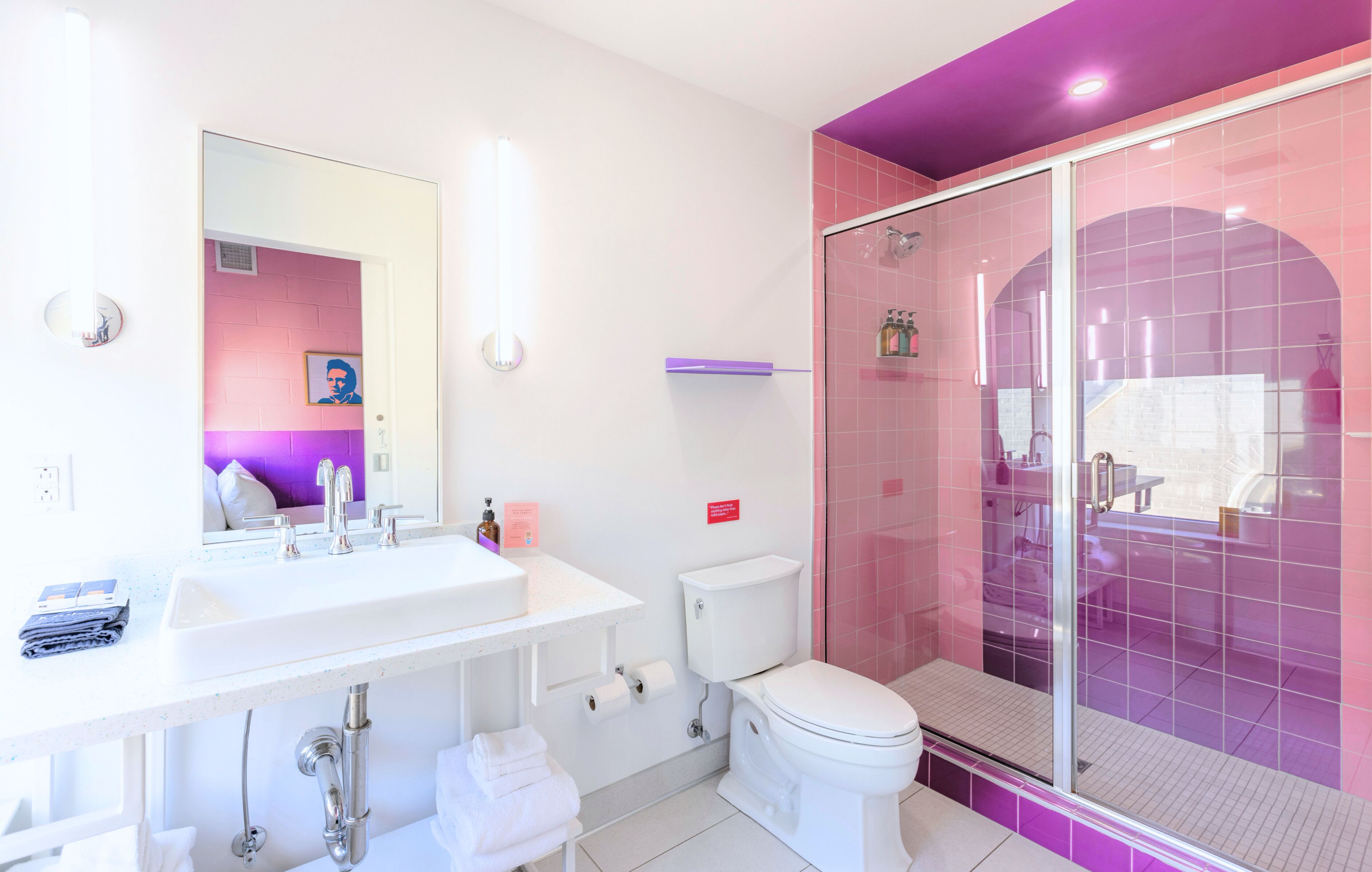 Une salle de bain moderne avec un lavabo blanc, un miroir, des toilettes et une douche à parois de verre.