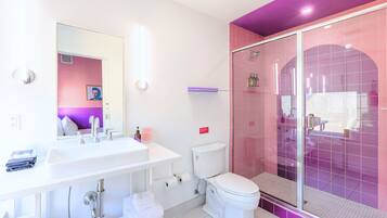 Un baño moderno con lavamanos, espejo, inodoro y cabina de ducha de vidrio.