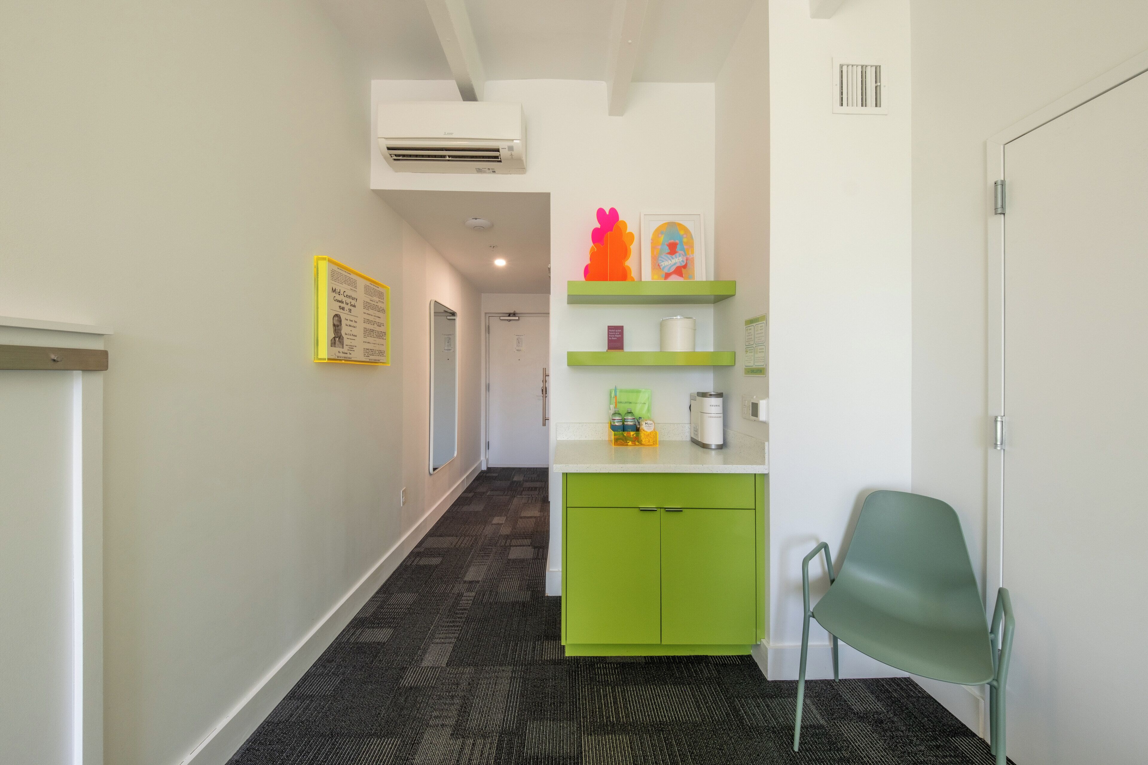 Un pasillo con un mostrador verde, una silla y una puerta.