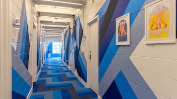 A hallway with patterned walls and carpet, doors, and framed artwork.