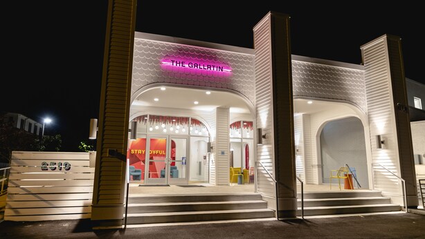 A modern building with a neon sign reading "THE GALLATIN" and a number "2510" on the entrance.