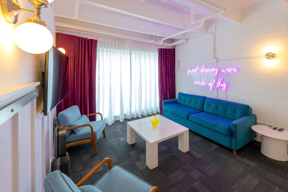 A modern living room with a blue sofa, a small white table, and a TV mounted on the wall.