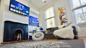 Un salon avec une cheminée, un téléviseur à écran plat fixé au mur, un canapé et un tapis.