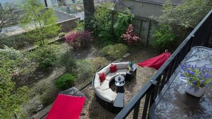 Un jardin sur le toit, avec un canapé incurvé, une couverture rouge et une petite table.
