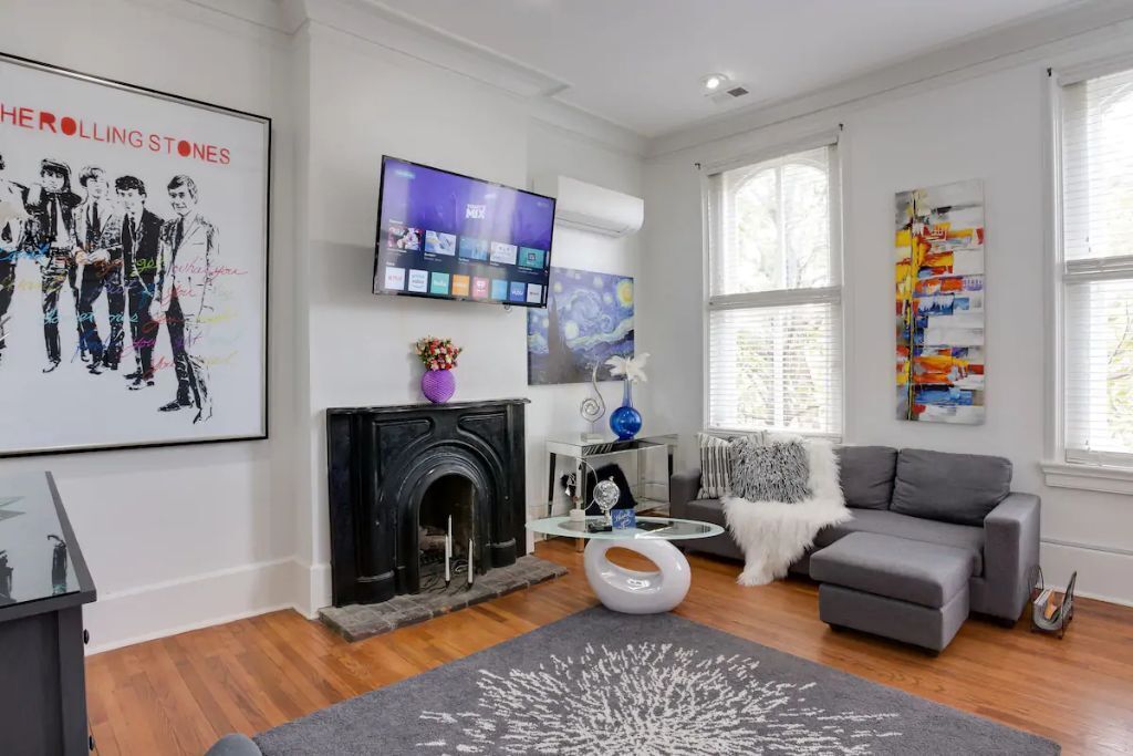 A modern living room with a fireplace, a flat-screen TV, and a grey sofa.