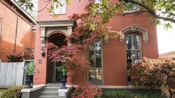 Un bâtiment en briques rouges, doté d’une entrée centrale, d’un petit porche et d’une boîte aux lettres portant le numéro « 669 ».